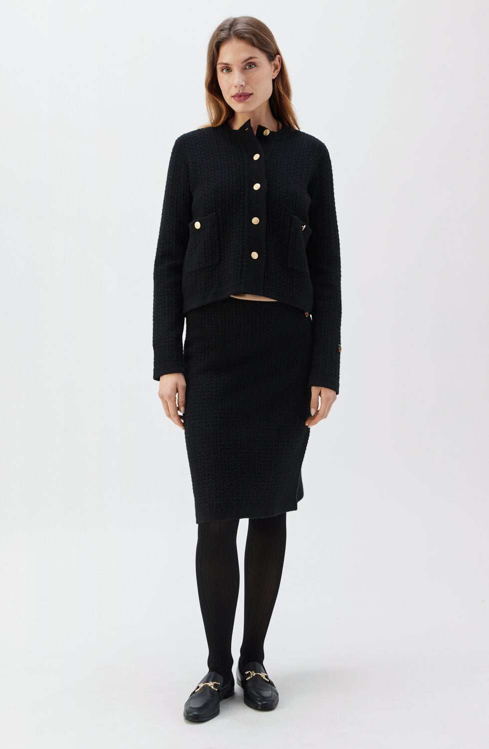 Woman wearing a black outfit with a jacket and skirt on a white background